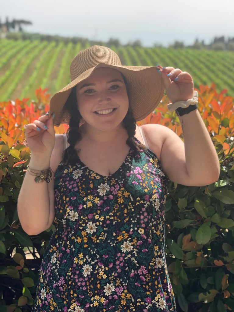 Sophia standing in front of a vineyard in Tuscany, Italy.